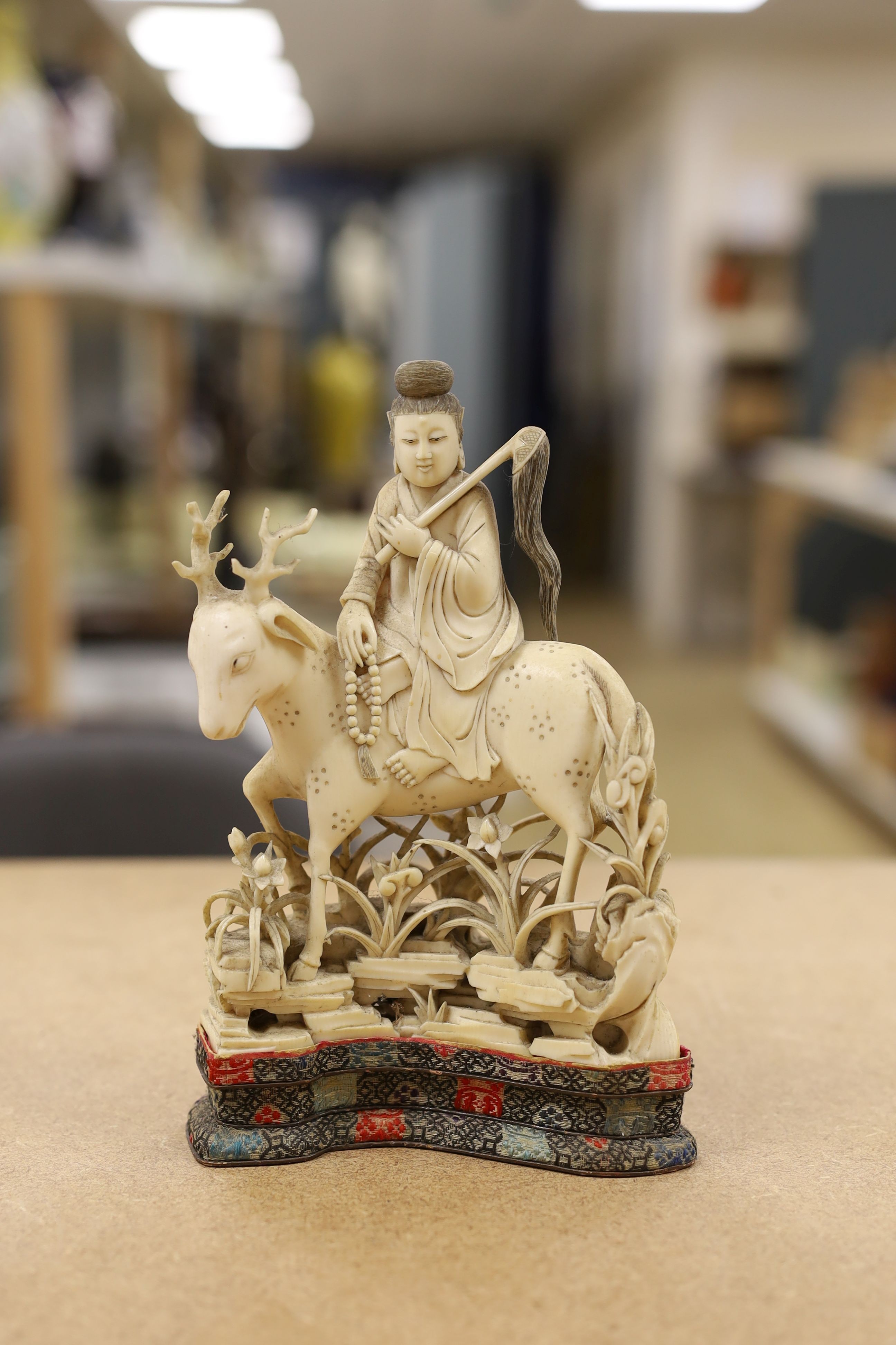 A Chinese carved ivory figure of a female immortal riding a deer, early 20th century, height 17cm excl. stand